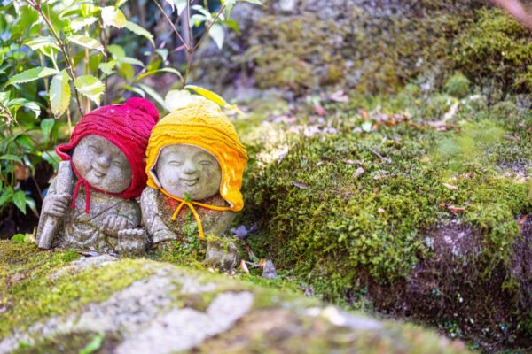 Kleine Jizō-Figuren zwischen Moos und Licht auf Miyajima, Japan