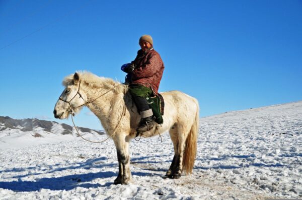 Reiter in auf einem verschneiten Feld in der Mongolei